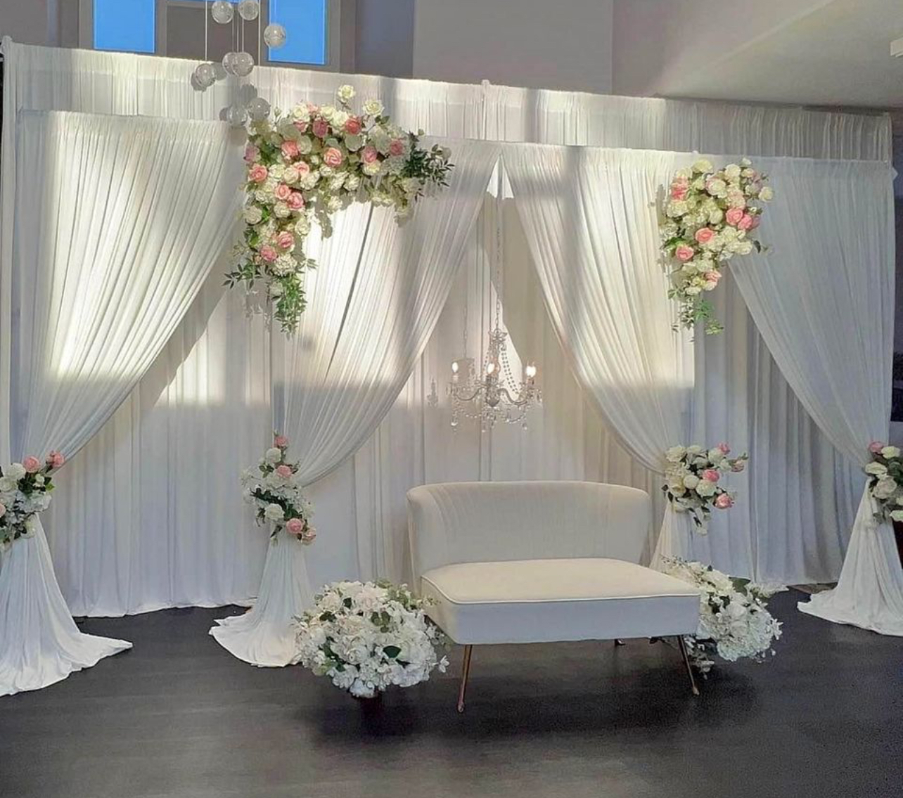 White drapery reception stage with pink florals and chandelier