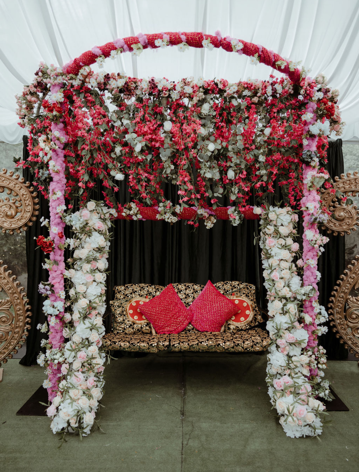 Red and white floral mandap with sweetheart sofa