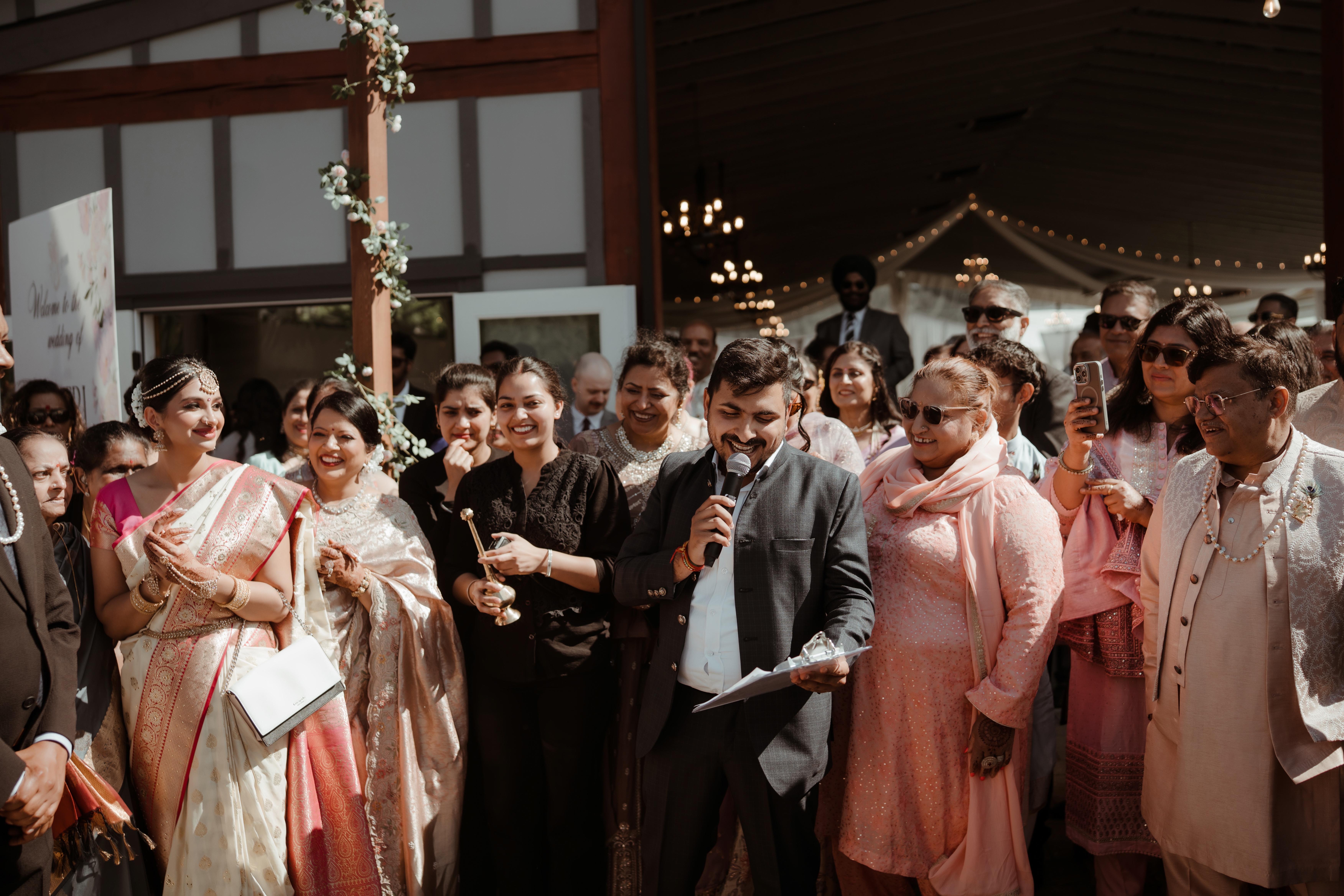 Nitesh welcoming guests with a microphone at an outdoor wedding